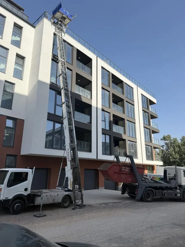 Автовишка със стрела, вдигната до фасадата на нова жилищна сграда