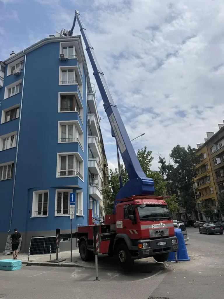 Автовишка със стрела, вдигната между две сгради